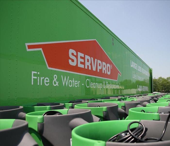 Large green truck with an orange SERVPRO logo and green air movers in front of the truck.