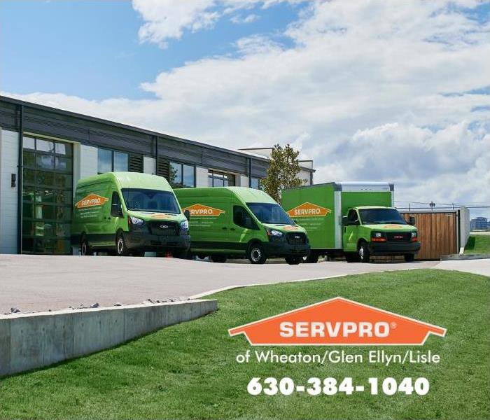 Three green SERVPRO trucks outside of the office warehouse.