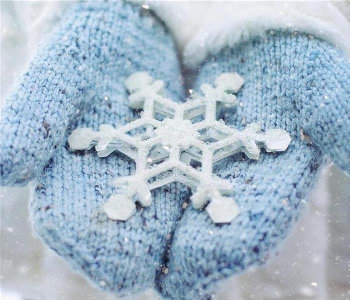 Blue winter mittens holding a big white snowflake.